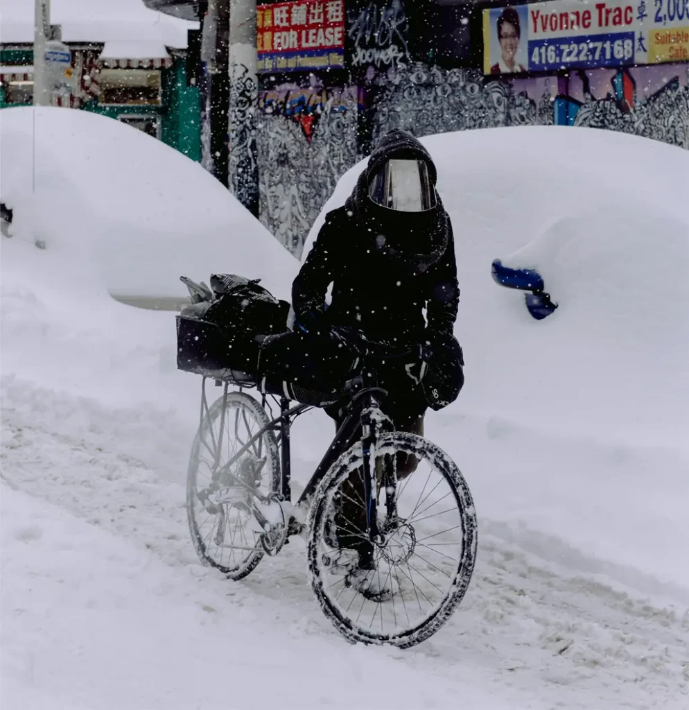 An unprepared man pulling his bike through the snow on his way to work